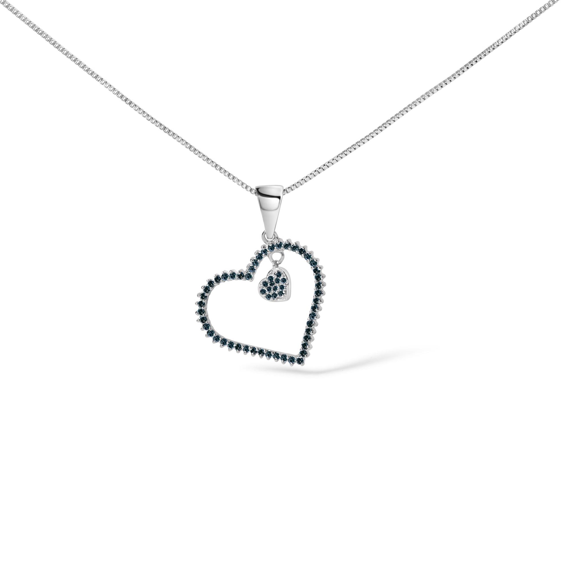 Close-up image of a white metal necklace with an open heart pendant outlined with blue round gemstones in prong settings and a smaller heart pendant inside, also encrusted with blue round gemstones, shown from a front angle on a white background.