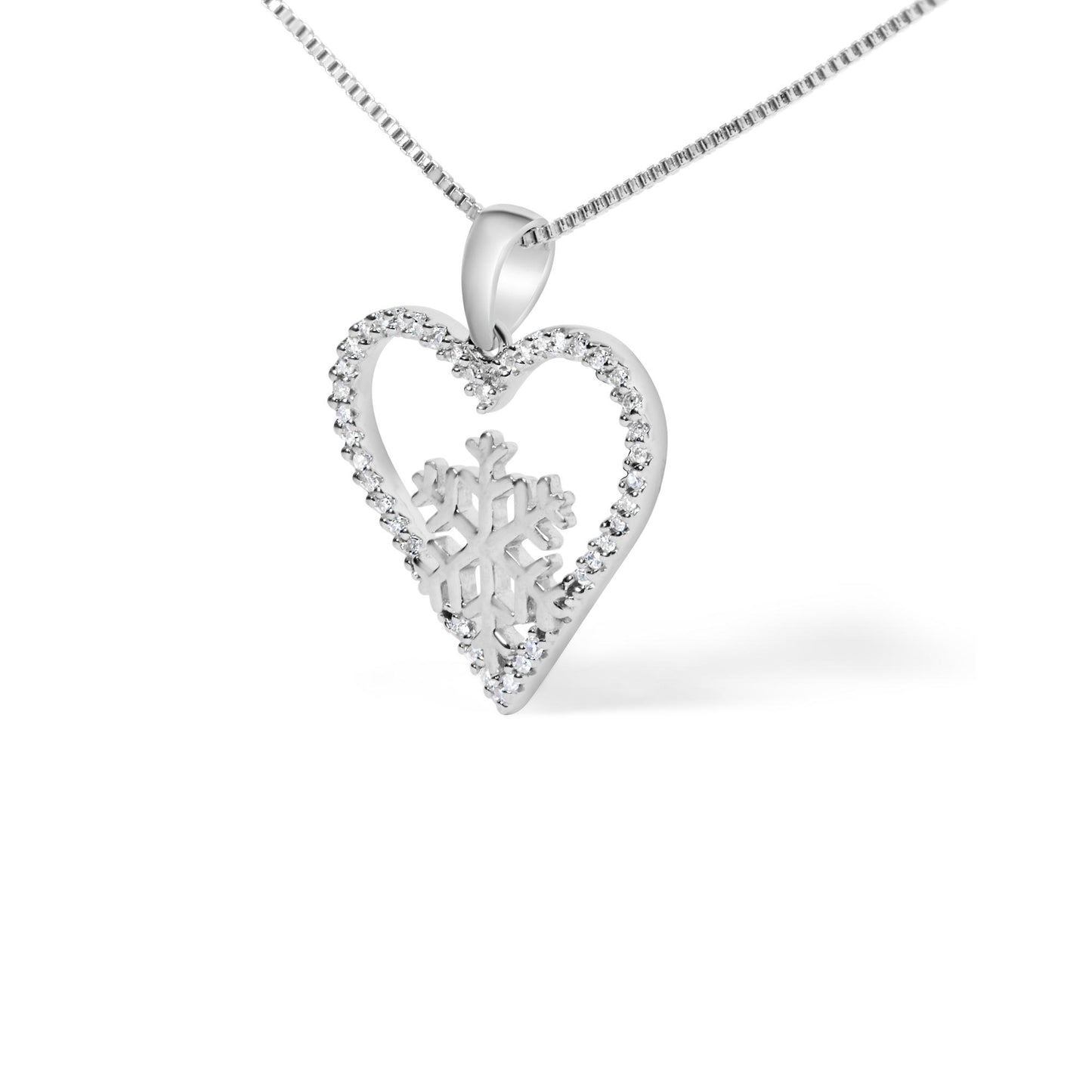 Close-up angled view of a white metal necklace pendant featuring an open heart shape lined with round white gemstones in prong settings, with a snowflake design inside the heart. The pendant is hung on a white metal chain.