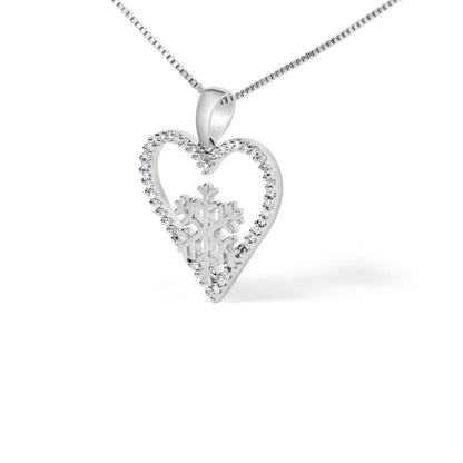 Close-up angled view of a white metal necklace pendant featuring an open heart shape lined with round white gemstones in prong settings, with a snowflake design inside the heart. The pendant is hung on a white metal chain.