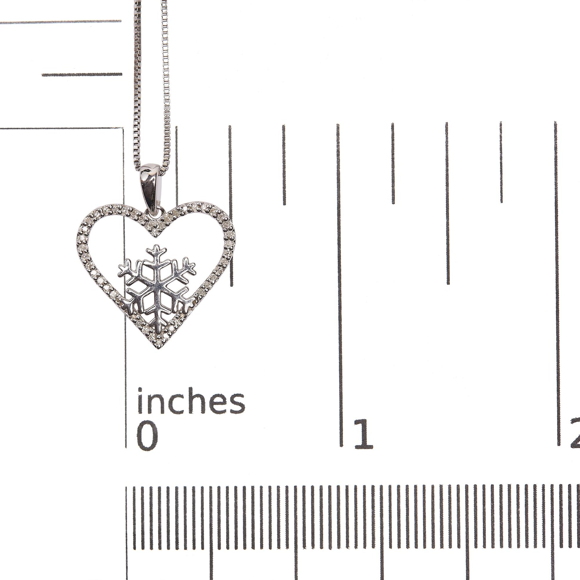 Close-up image of a white necklace pendant with a heart shape adorned with white gemstones set in prongs along the edge and a snowflake design inside, shown on a scale.