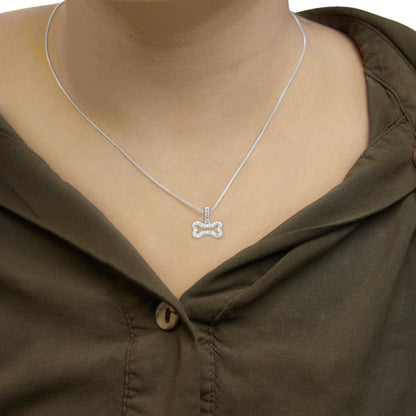 Close-up front view of a white metal necklace on a model, featuring a bone-shaped pendant adorned with round white gemstones in prong settings.