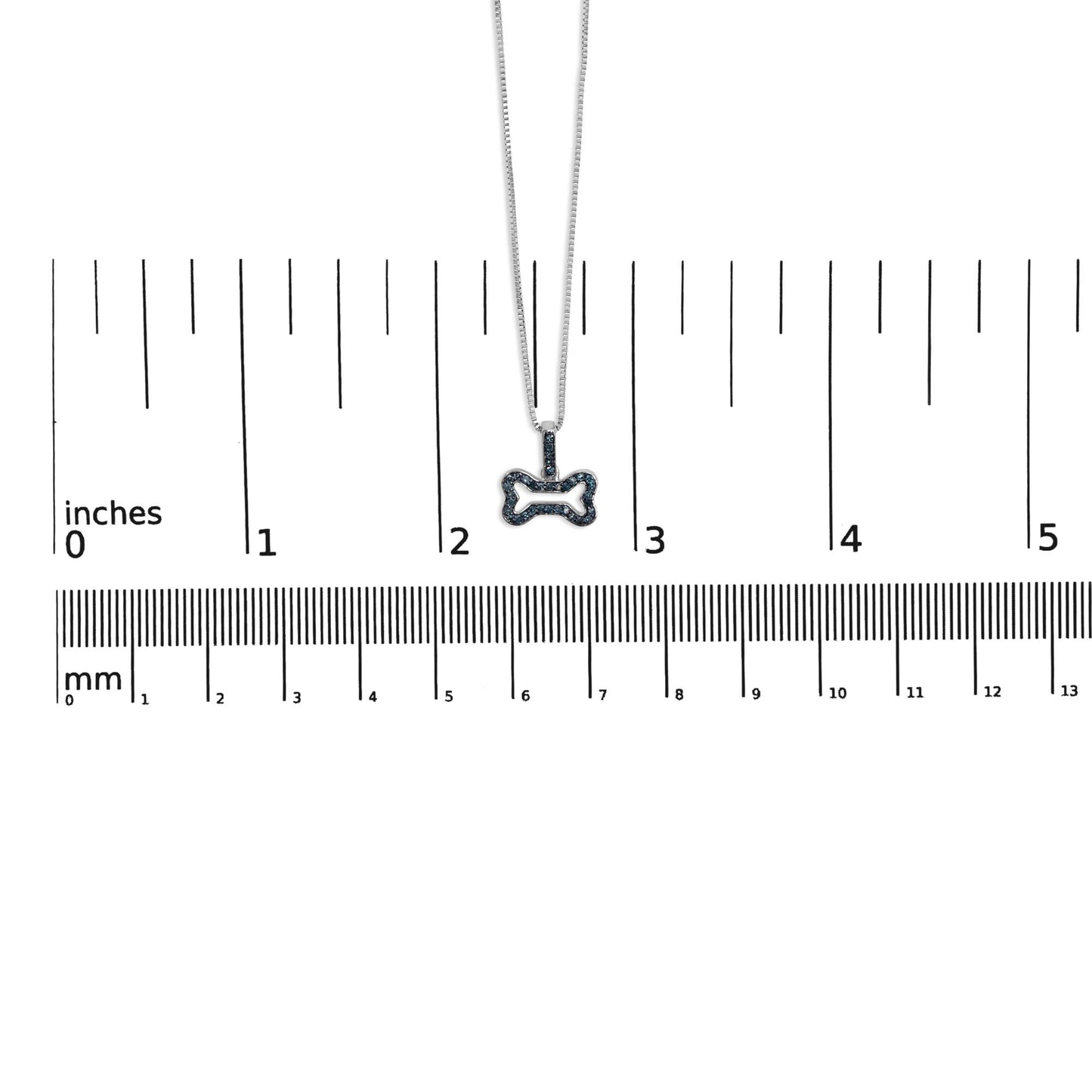 White metal necklace with bone-shaped pendant set with round blue gemstones in prong settings, shown hanging centered above a ruler for size reference, front view.