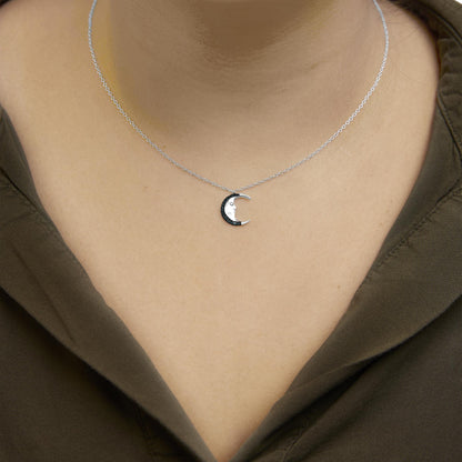 Close-up front view of a white metal necklace on a model with a crescent moon pendant adorned with round blue gemstones in a prong setting.