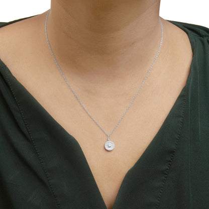 Close-up front view of a white metal necklace with a round pendant featuring a cluster of white gemstones, worn on a model.