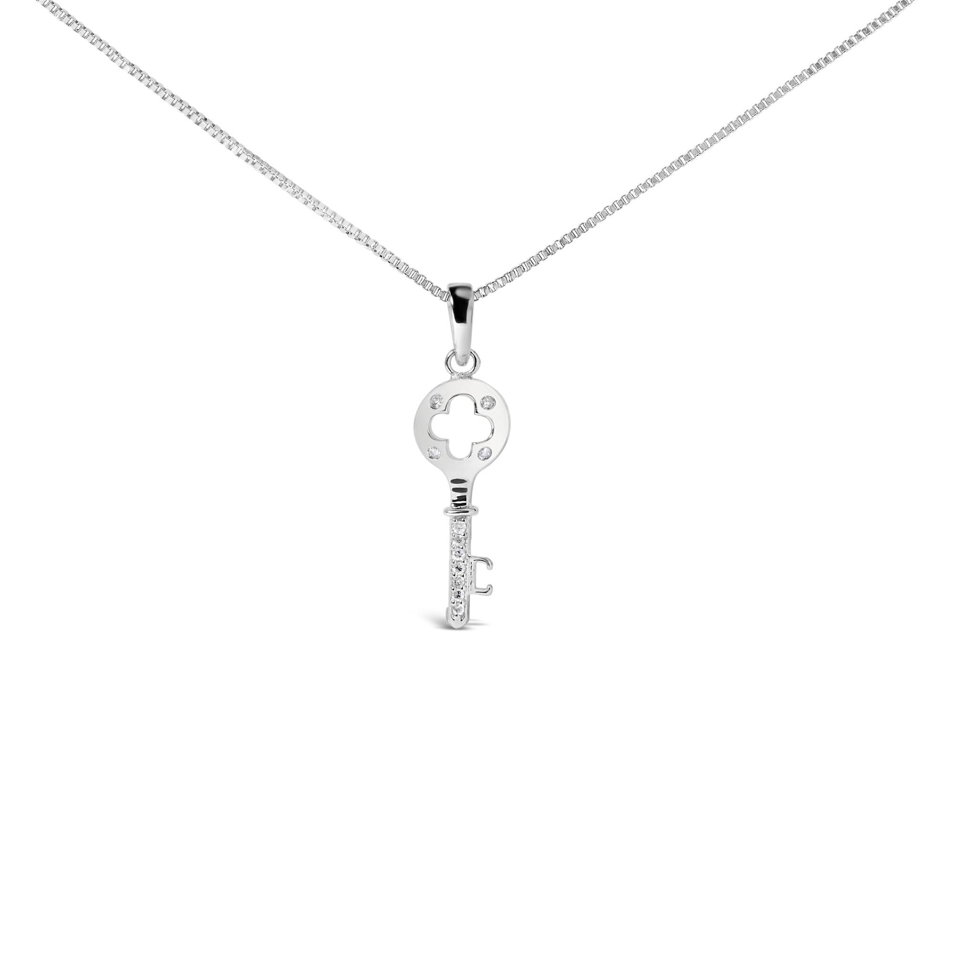 Front angle view of a white metal key-shaped necklace pendant with round white gemstones in prong settings on the circular top and along the shaft, suspended on a box chain.