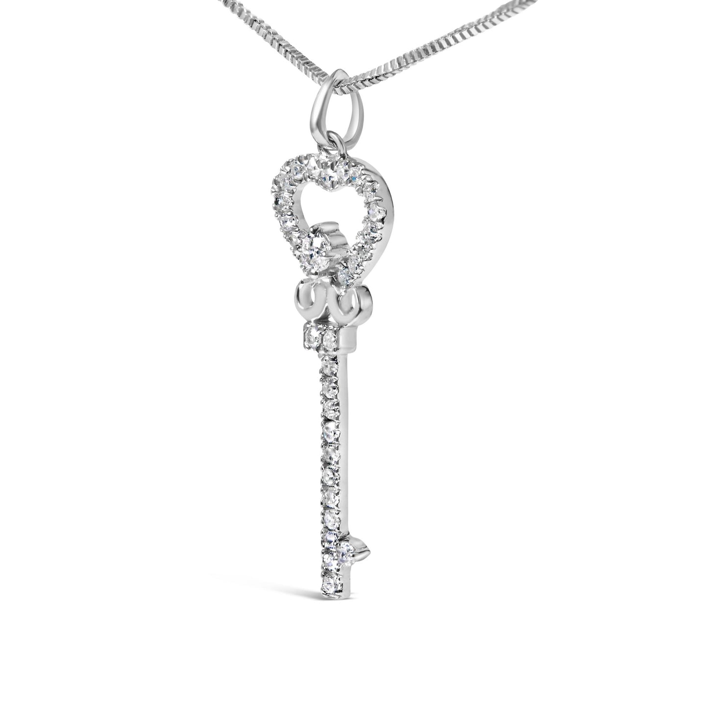 Close-up front angle of a white metal key-shaped necklace pendant with a heart outline adorned with round white gemstones in prong settings, hanging from a chain.
