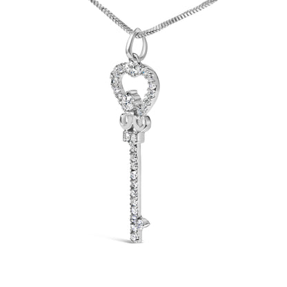 Close-up front angle of a white metal key-shaped necklace pendant with a heart outline adorned with round white gemstones in prong settings, hanging from a chain.