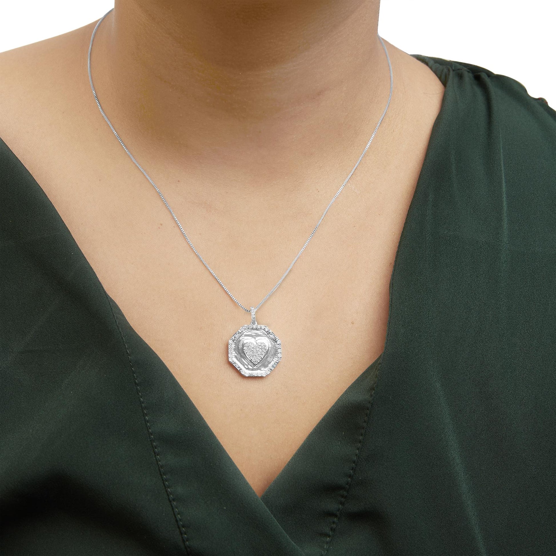 White metal necklace with a heart-shaped pendant featuring round and baguette white gemstones, worn on a model, front-facing angle.