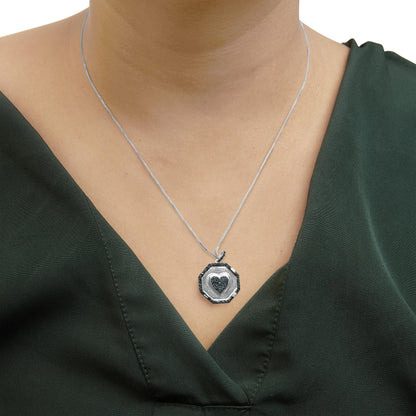 Close-up front view of a white metal necklace with an octagonal pendant featuring a heart shape in the center, both accented with blue round and baguette gemstones, worn on a model.