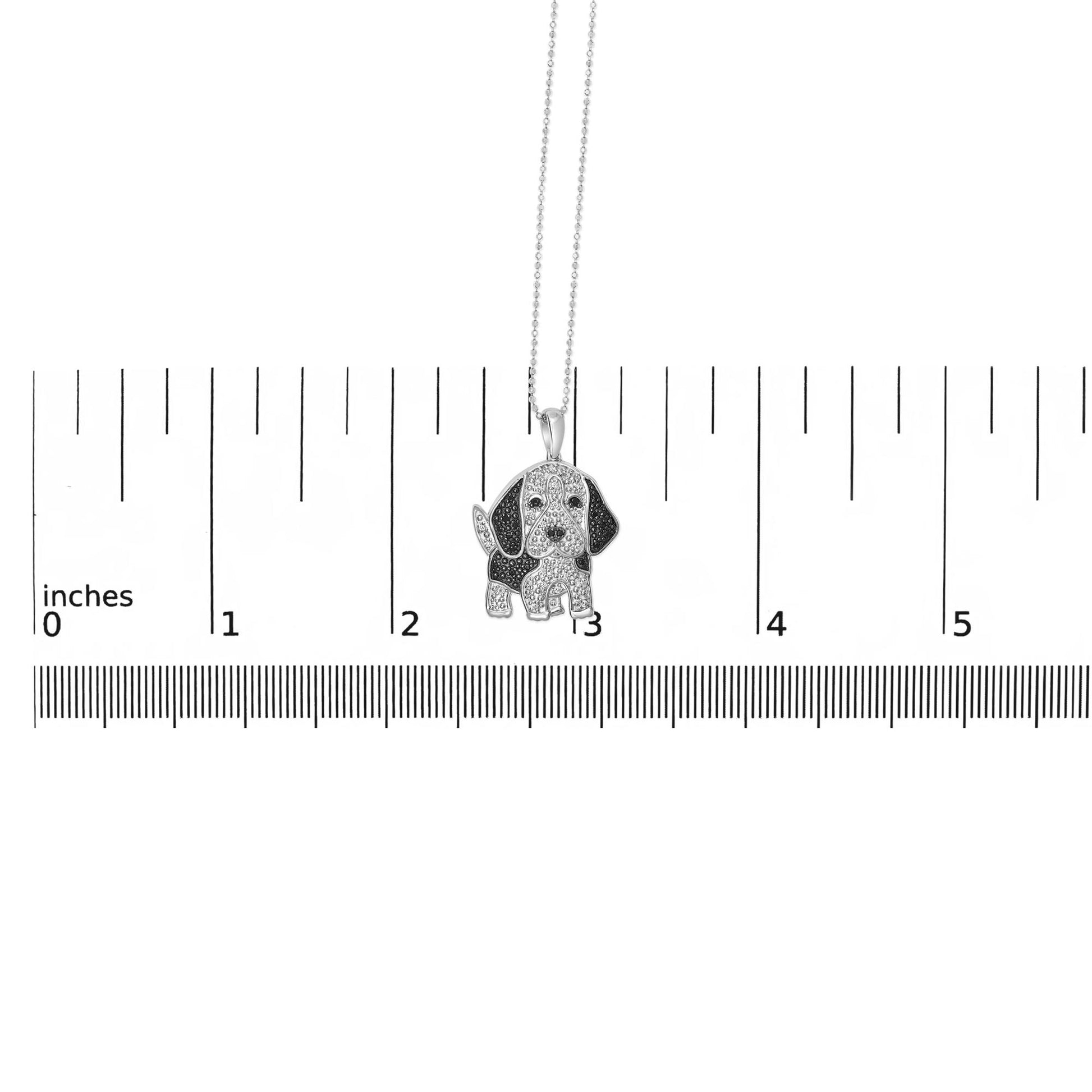 White metal necklace with a dog-shaped pendant featuring micro-pave white and black gemstones, displayed hanging above a ruler for size reference, front angle.
