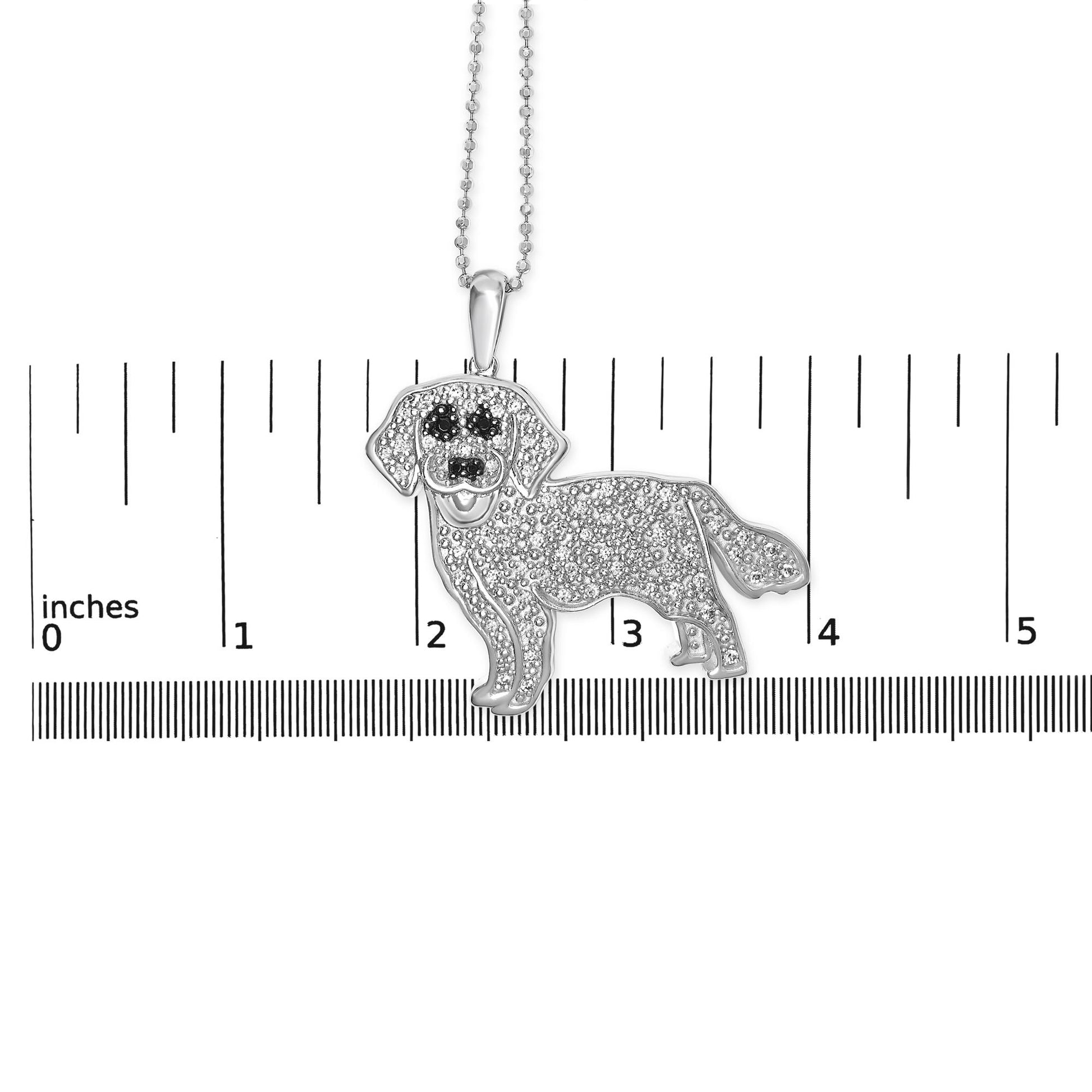 Front view of a white metal dog-shaped pendant necklace with micro-pave white and black gemstones, displayed on a ruler for size reference.
