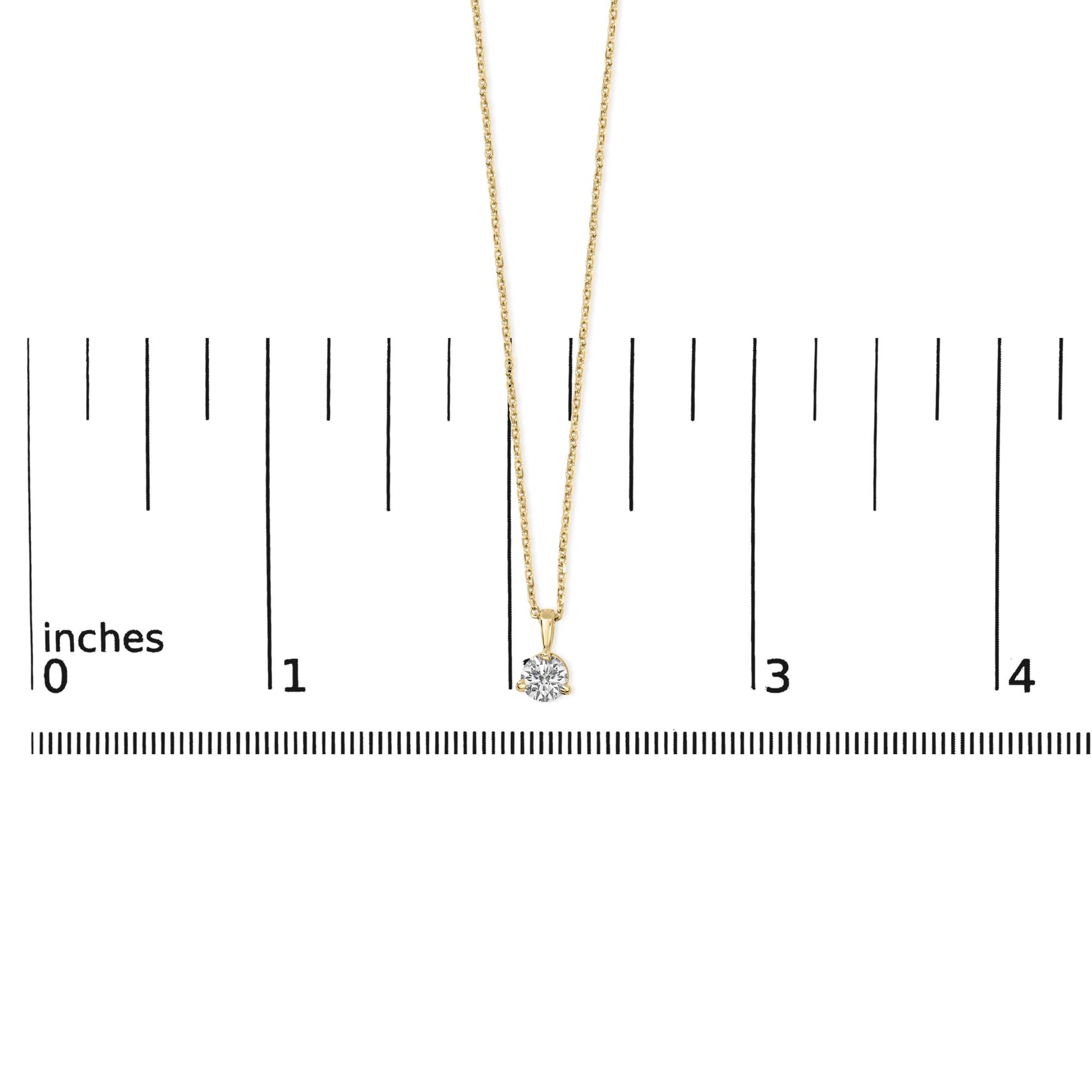 Yellow metal necklace with a round white gemstone in a three-prong setting, photographed from the front on a ruler for size reference.