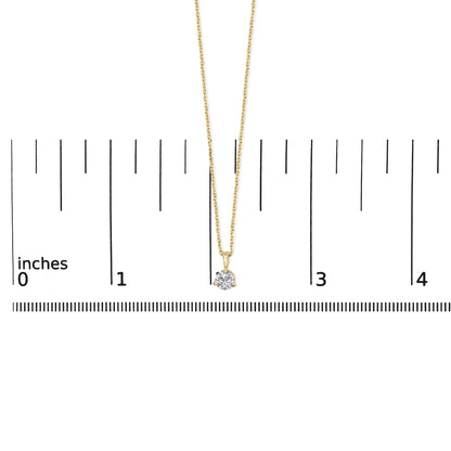 Yellow metal necklace with a round white gemstone in a three-prong setting, photographed from the front on a ruler for size reference.