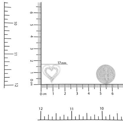 Close-up front view of a white metal heart-shaped necklace pendant with prong-set round white gemstones, shown on a ruler and next to a dime for size reference.