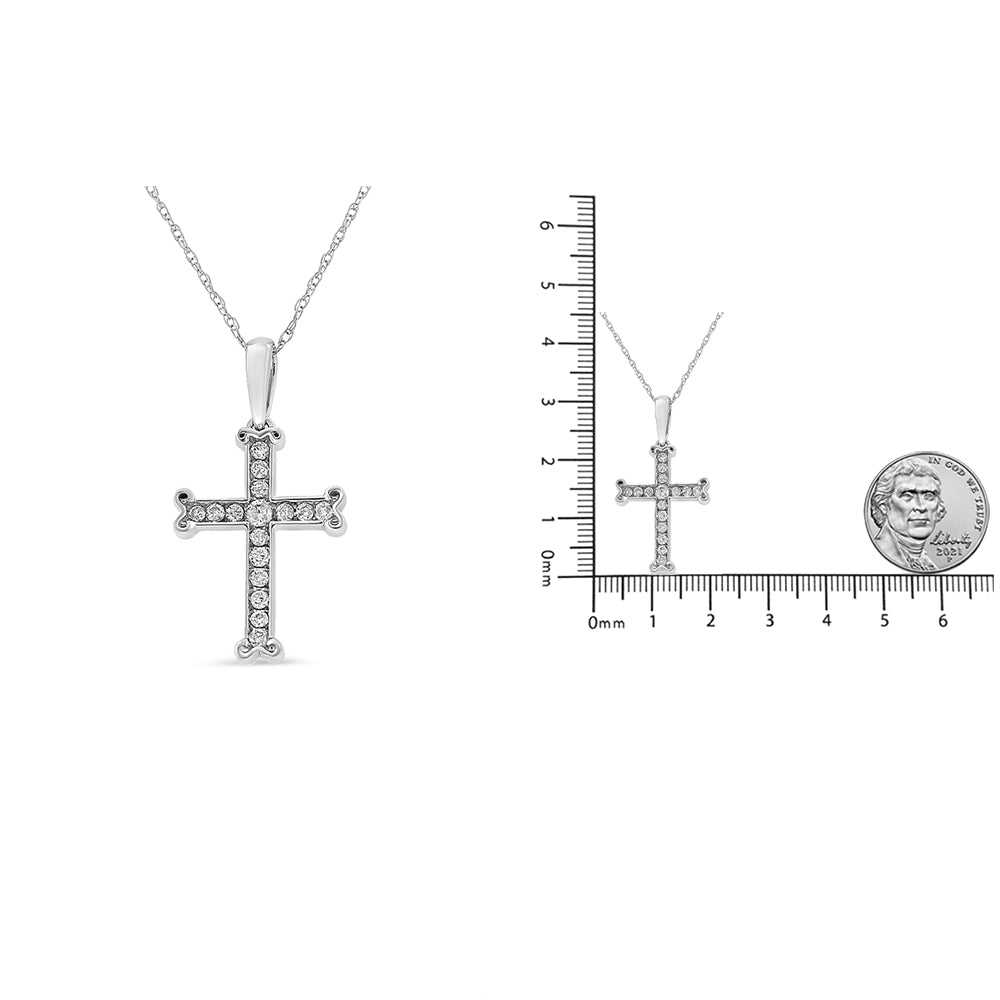 Front view of a white metal cross-shaped necklace pendant set with multiple round white gemstones in a channel setting, shown next to a scale with a coin for size reference.