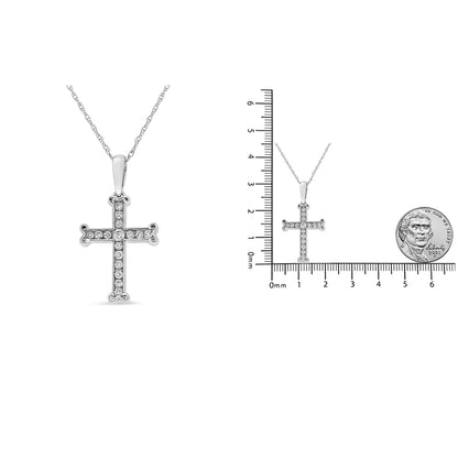 Front view of a white metal cross-shaped necklace pendant set with multiple round white gemstones in a channel setting, shown next to a scale with a coin for size reference.