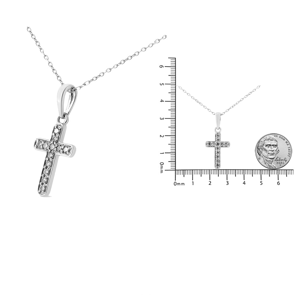 White metal cross necklace with round white gemstones in prong settings, shown in close-up and next to a ruler and coin for size reference, front angle.