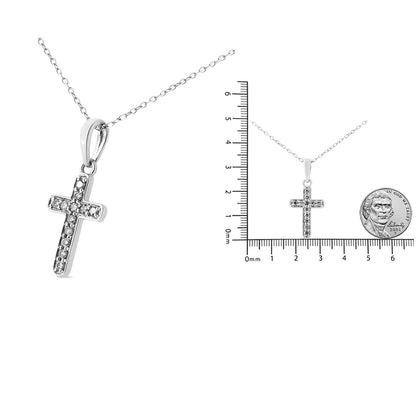 White metal cross necklace with round white gemstones in prong settings, shown in close-up and next to a ruler and coin for size reference, front angle.