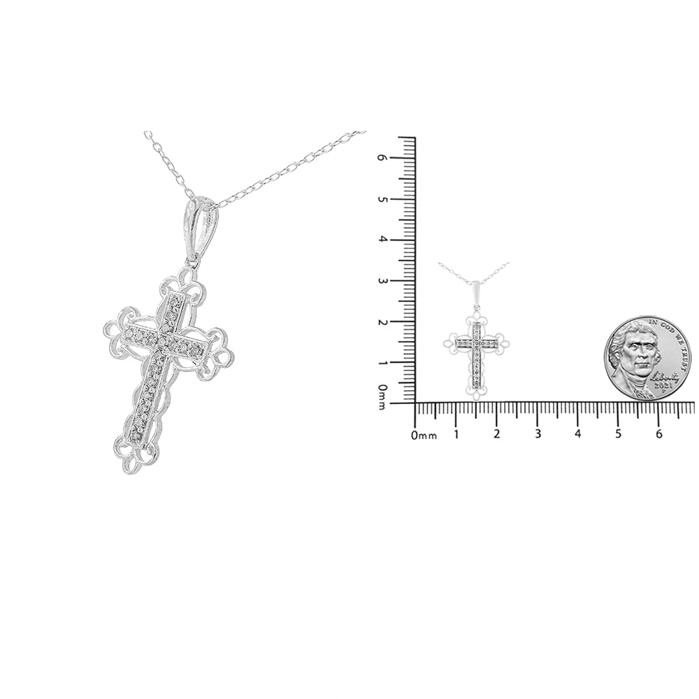 White metal cross necklace with round white gemstones in prong settings, front angle, shown next to ruler and coin for size reference.