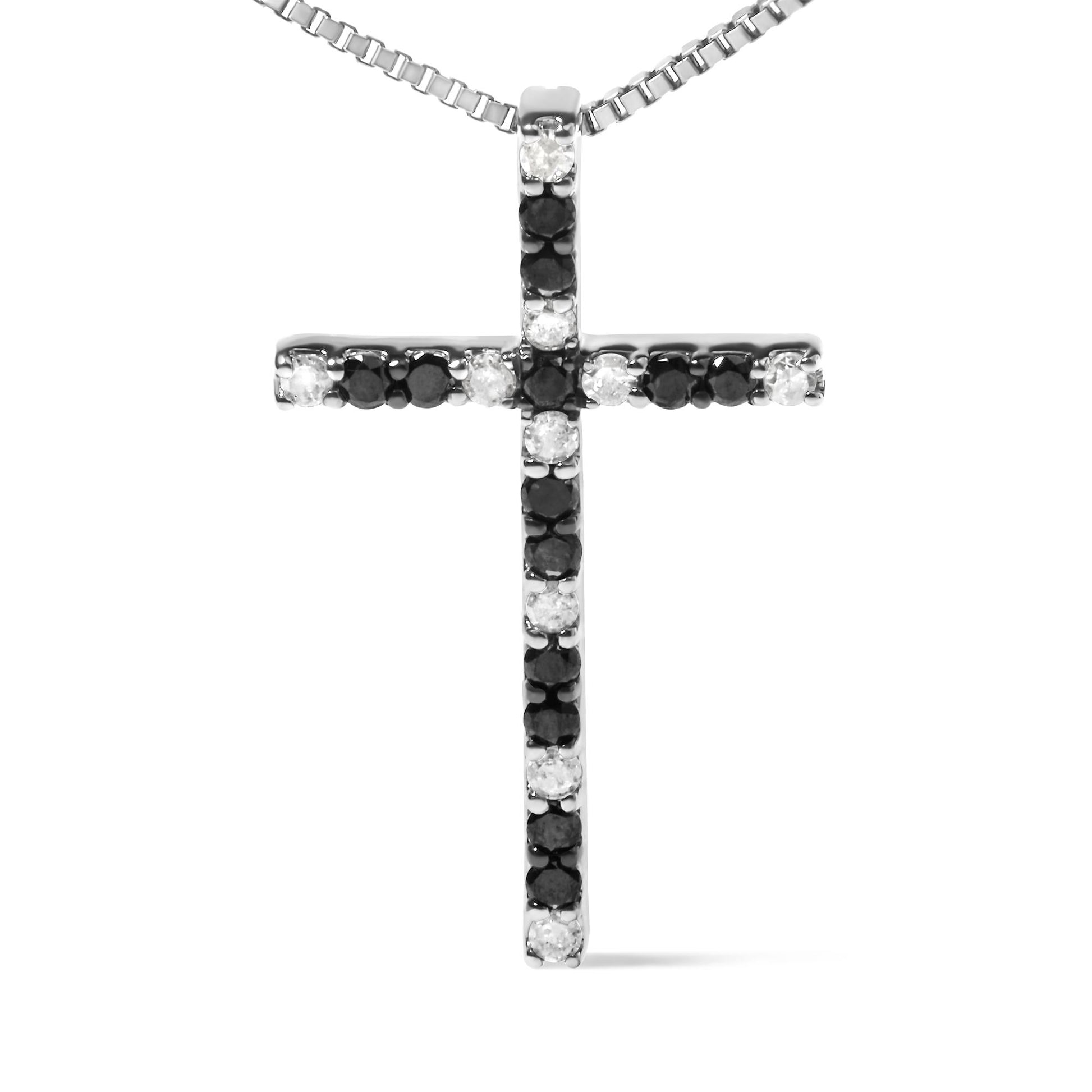 Front-facing shot of a white metal cross necklace pendant set with alternating black and white round prong-set gemstones.