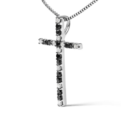 White metal cross necklace pendant with round prong-set black and white gemstones, shown at a slight angle on a matching chain.