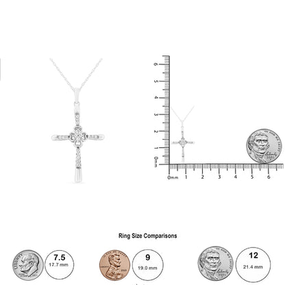 Front view of a white metal cross necklace with round white gemstones in prong settings, shown alongside a ruler and coin for size reference.