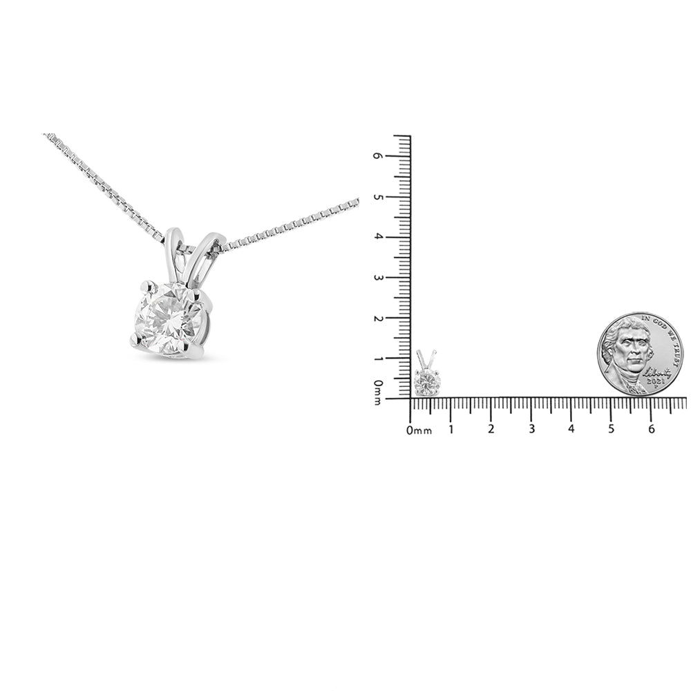 Close-up angled shot of a white necklace with a round white gemstone in a four-prong setting, shown next to a ruler and coin for size reference.