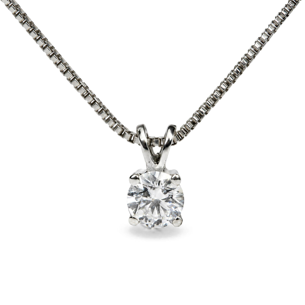 Close-up front view of a white metal necklace with a pendant featuring a single round white gemstone in a four-prong setting.