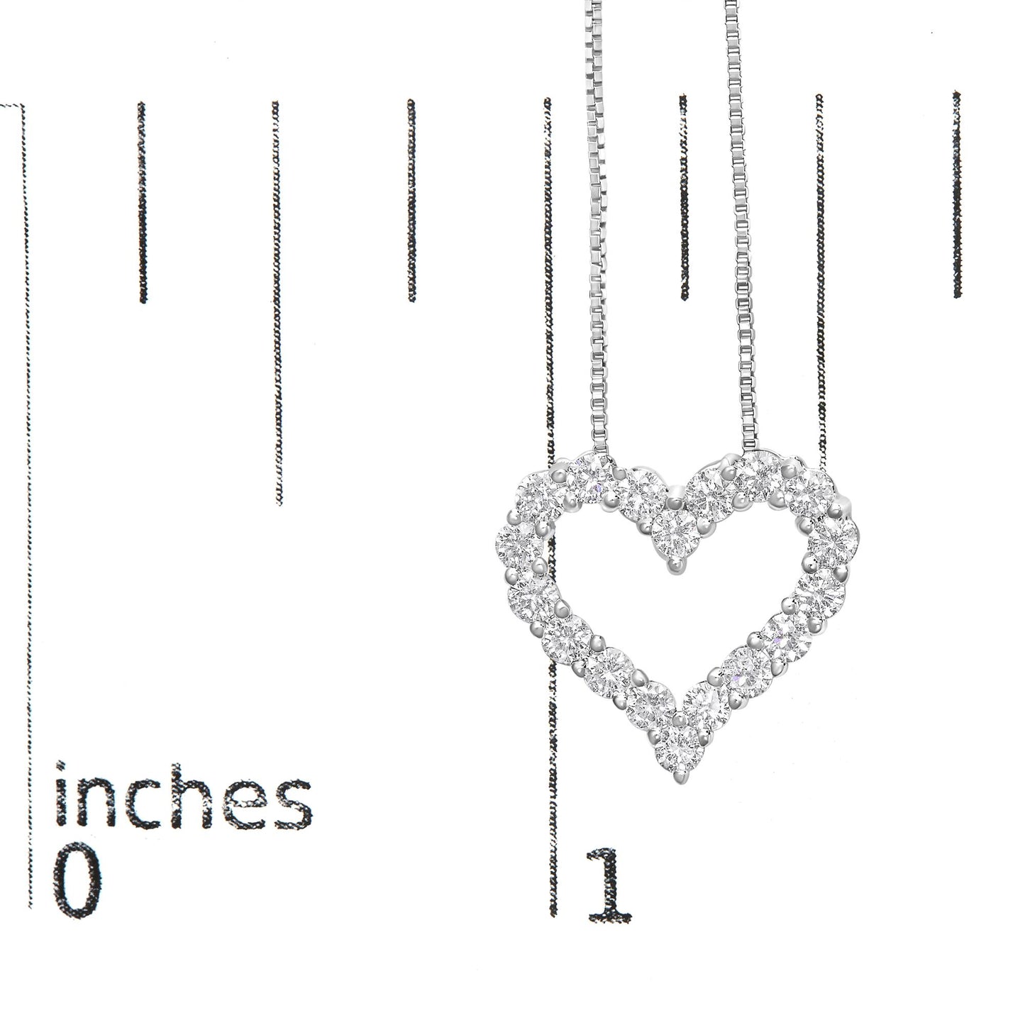 Close-up of a white metal heart-shaped necklace pendant with round white gemstones in prong settings, shown hanging against a ruler for size reference.