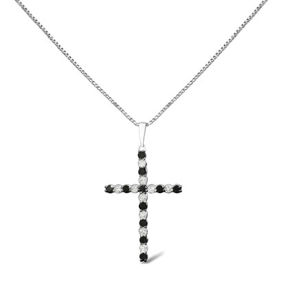 Front-facing shot of a white metal cross-shaped necklace pendant featuring alternating round white and black gemstones in prong settings on a white metal chain.