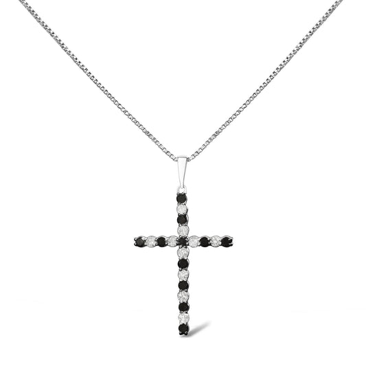 Front-facing shot of a white metal cross-shaped necklace pendant featuring alternating round white and black gemstones in prong settings on a white metal chain.