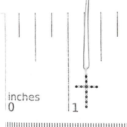 White metal cross necklace with alternating black and white round gemstones in prong settings, shown hanging on a ruler for size reference, front-facing angle.