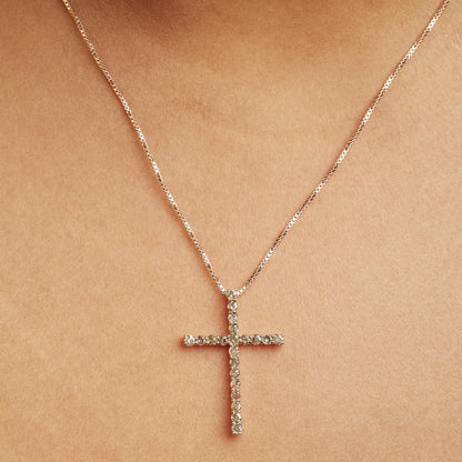 Rose metal necklace with a cross pendant featuring round champagne-colored gemstones in prong settings, shown on a model from a front close-up angle.