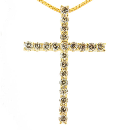 Close-up front view of a yellow metal cross necklace pendant with round brownish prong-set gemstones.
