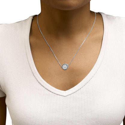 Close-up front view of a necklace with a white metal chain and a round bezel-set white gemstone pendant, shown worn on a model's neck.