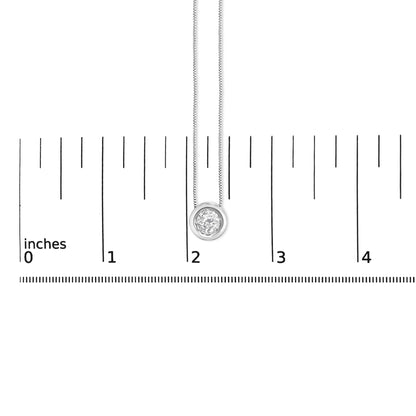 Close-up front view of a white metal necklace with a round bezel-set white gemstone pendant shown on a scale marked in inches.