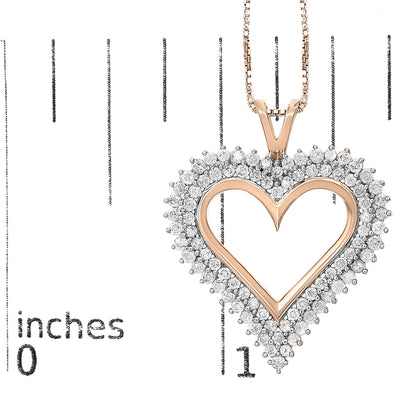 Close-up front view of a rose-colored heart-shaped necklace pendant with round white gemstones in prong settings surrounding the heart, placed on a ruler for size reference.