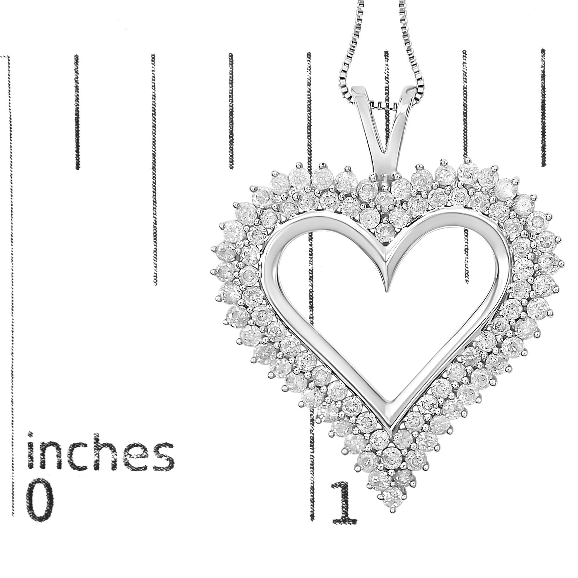 Close-up of a white metal heart-shaped necklace pendant with round white gemstones in prong settings, shown against a ruler for size reference.