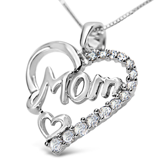 Close-up angled view of a white metal necklace pendant shaped like a heart with the word 'Mom' in script inside, accented with prong-set round white gemstones along one side and a small heart near the bottom.
