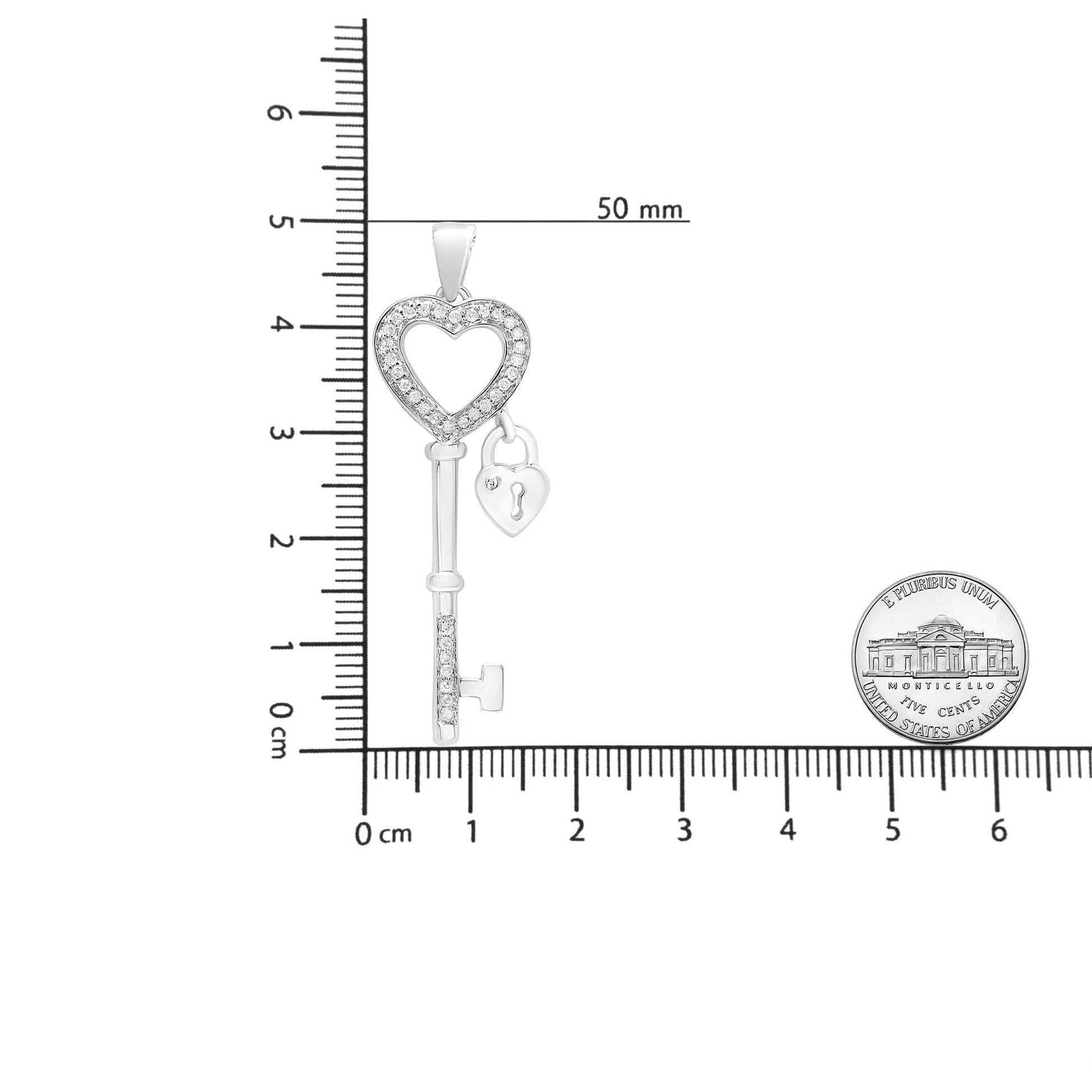 White metal heart-shaped key pendant necklace with round white gemstones in prong setting, shown in vertical position on a ruler for size reference.