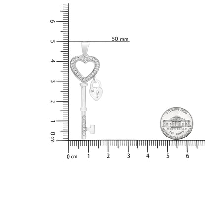 White metal heart-shaped key pendant necklace with round white gemstones in prong setting, shown in vertical position on a ruler for size reference.