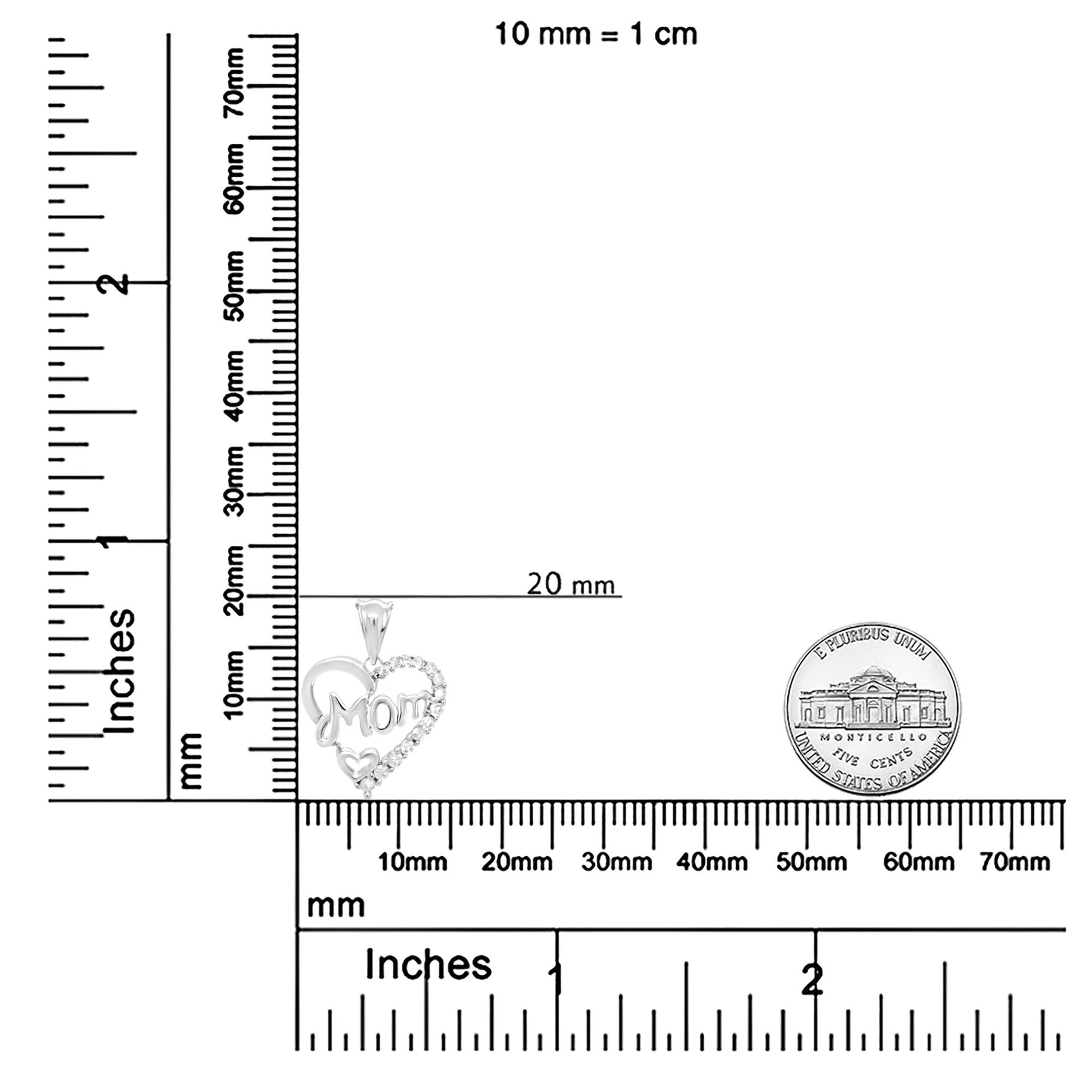 Close-up front view of a white necklace pendant with a heart design, featuring 'Mom' text and multiple round white gemstones in prong settings, shown on a ruler and scale for size reference.
