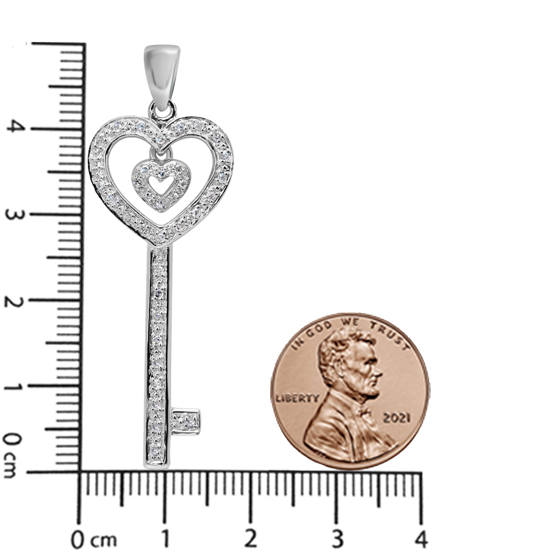 White metal key-shaped necklace pendant with two heart designs set with round white gemstones, shown on a ruler and next to a coin for size reference, front-facing angle.