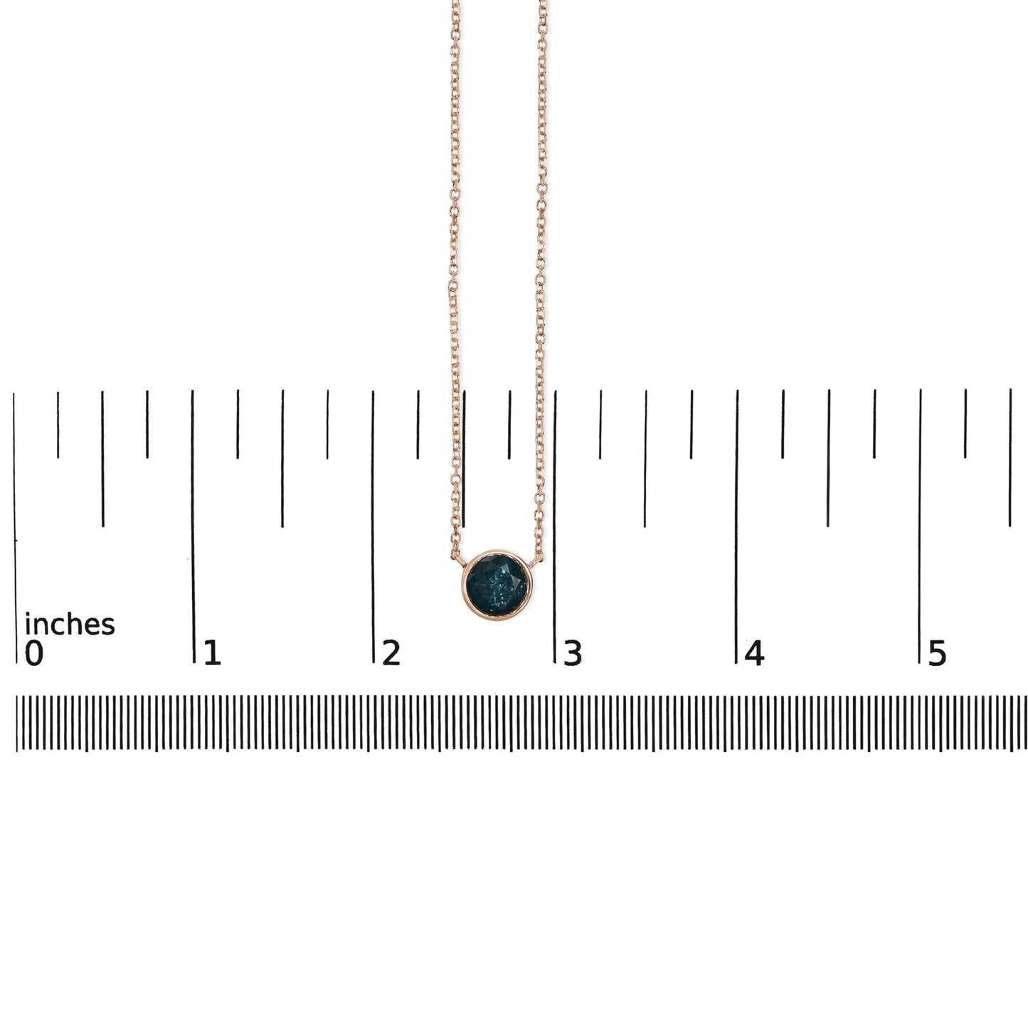 Rose metal necklace with a round blue gemstone in bezel setting, shown hanging vertically on a scale with measurement markings, front view.