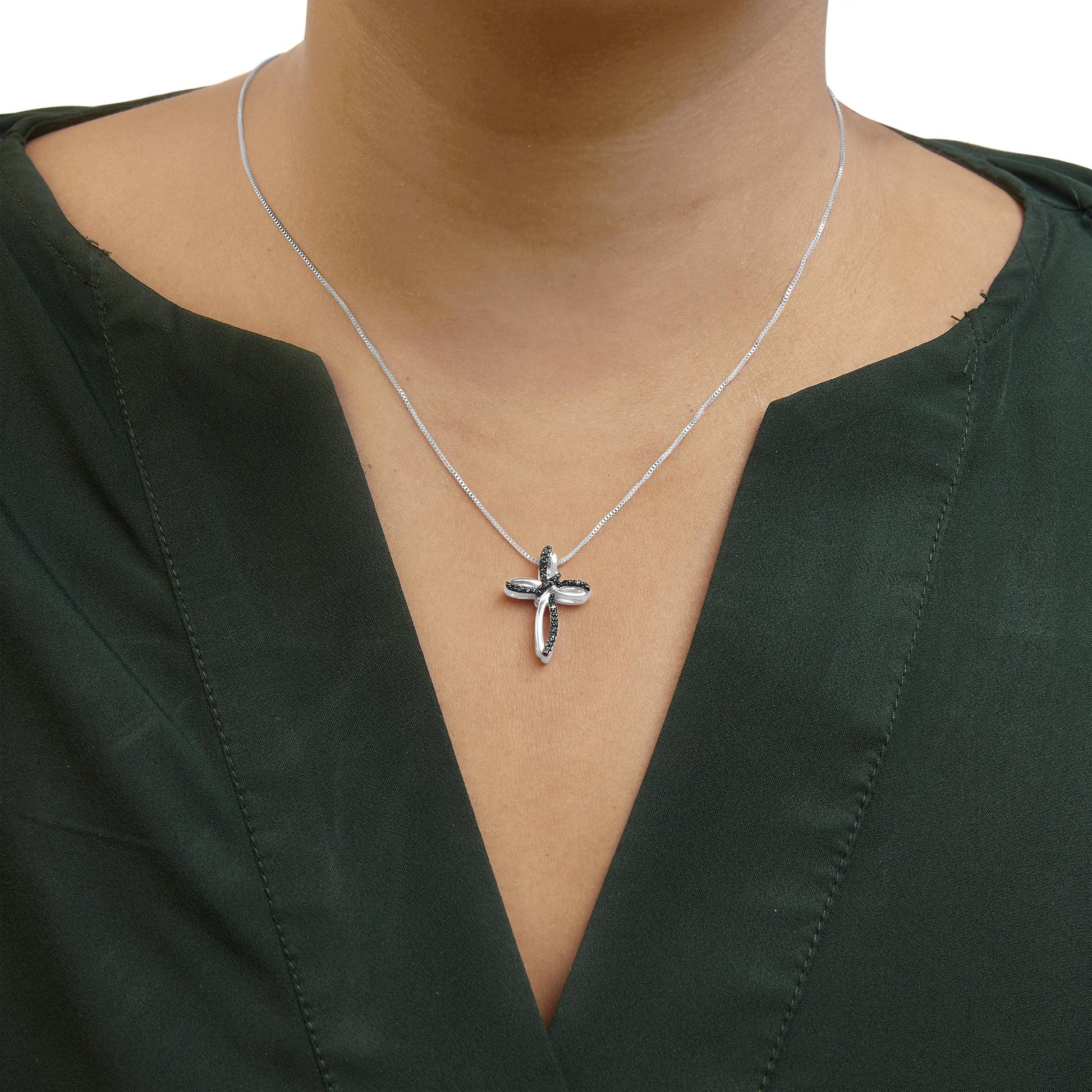 White metal necklace with cross-shaped pendant featuring prong-set round blue gemstones, shown on a model from front angle.