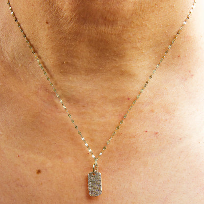 Close-up front view of a yellow metal necklace with a rectangular pendant encrusted with multiple rows of round white gemstones in prong settings, worn on a model.