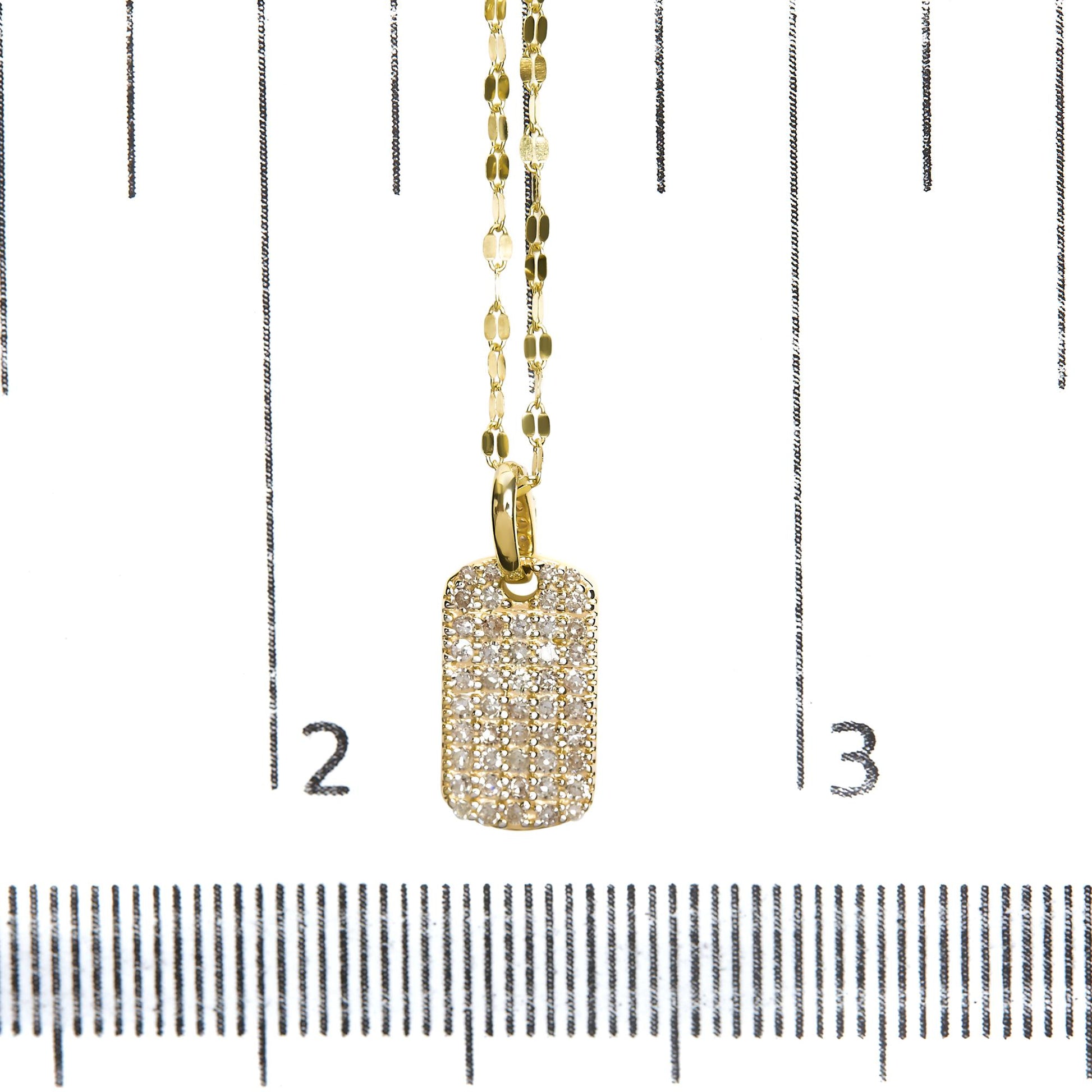 Close-up front view of a yellow metal necklace with a rectangular pendant encrusted with multiple white round gemstones, displayed on a ruler for size reference.