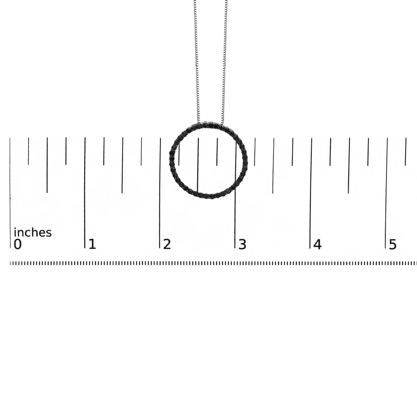 White metal necklace with circular pendant featuring round black gemstones in shared prong setting, shown hanging above a ruler for size reference, front view.