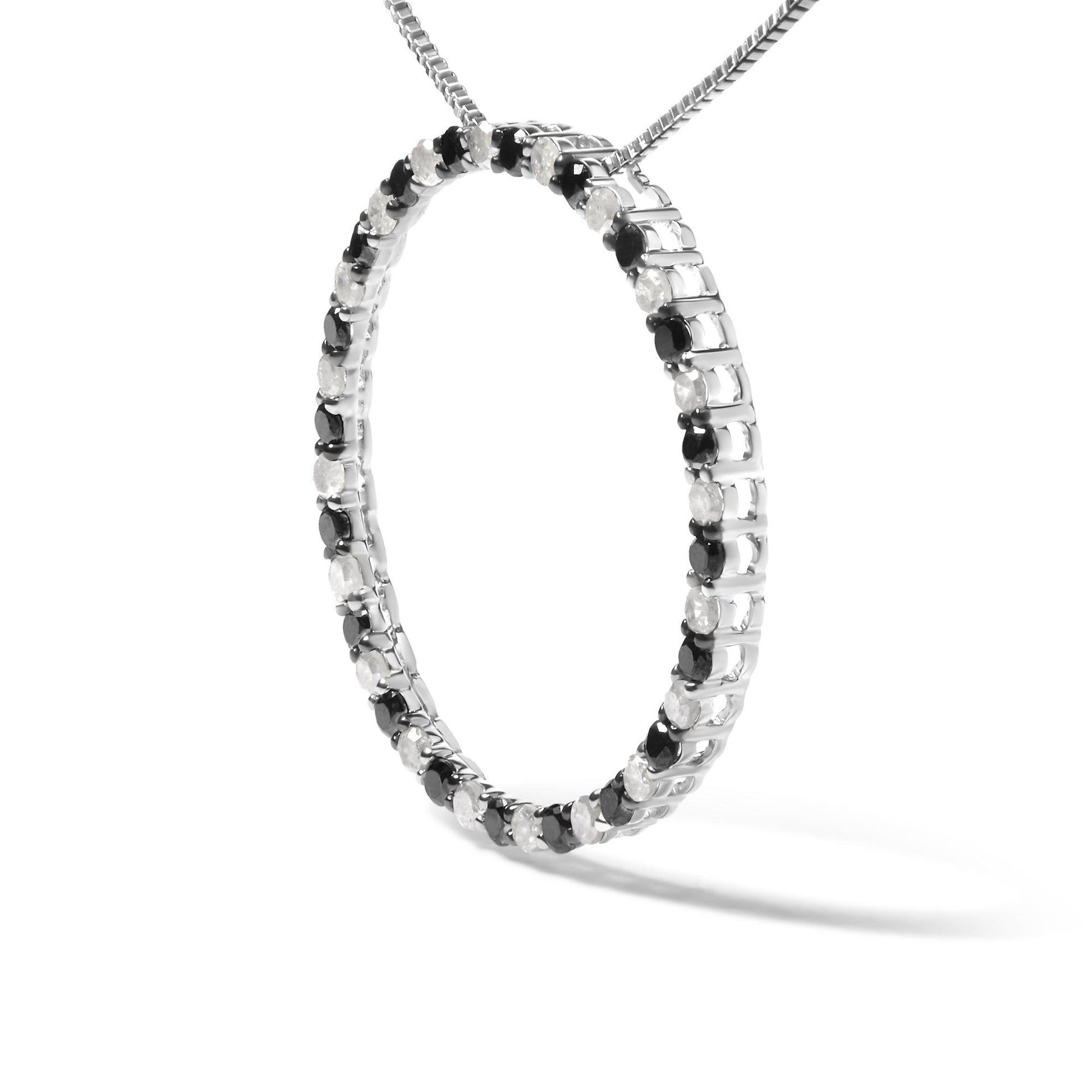 Close-up front angled view of a white metal necklace pendant in a circular hoop shape set with alternating round black and white gemstones in prong settings, shown on a chain against a white background.