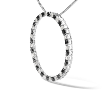 Close-up front angled view of a white metal necklace pendant in a circular hoop shape set with alternating round black and white gemstones in prong settings, shown on a chain against a white background.